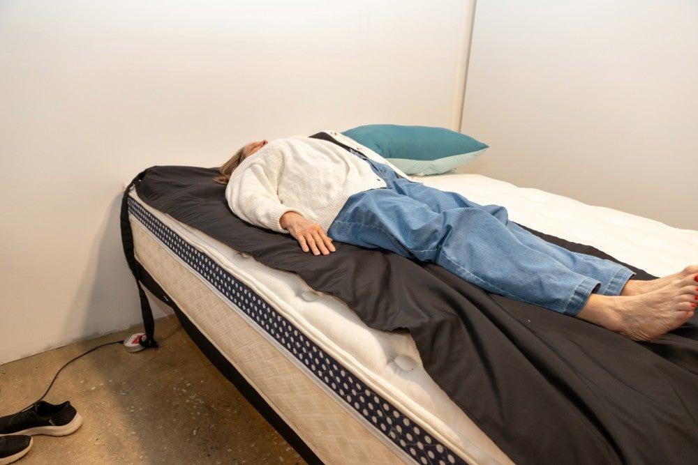 A woman lying on her back on the WinkBed Luxury Firm mattress with a pressure map laid on top of it
