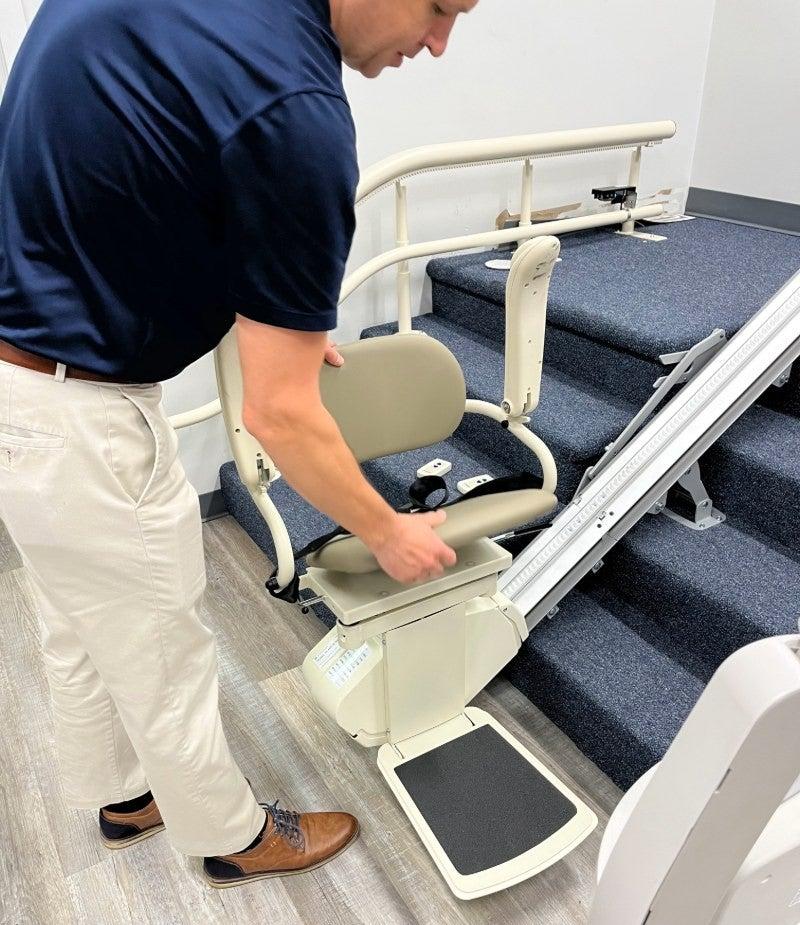 A man unfolds the Harmar SL300 Pinnacle stairlift in a showroom setting