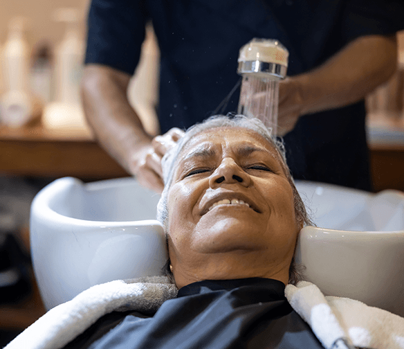 smiling older woman having hair washed in sink at salon