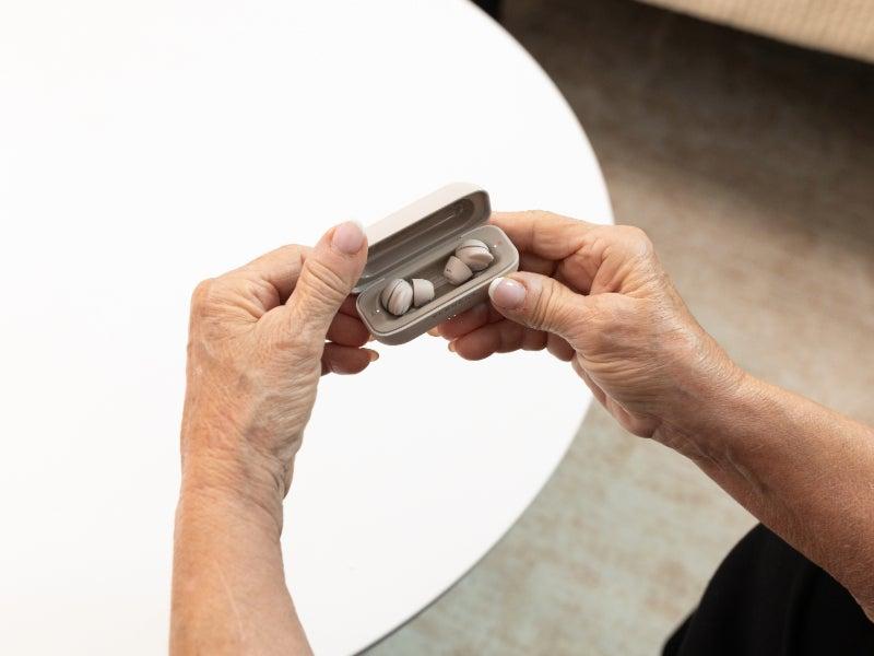 A person opening the Elehear Delight hearing aids charging case