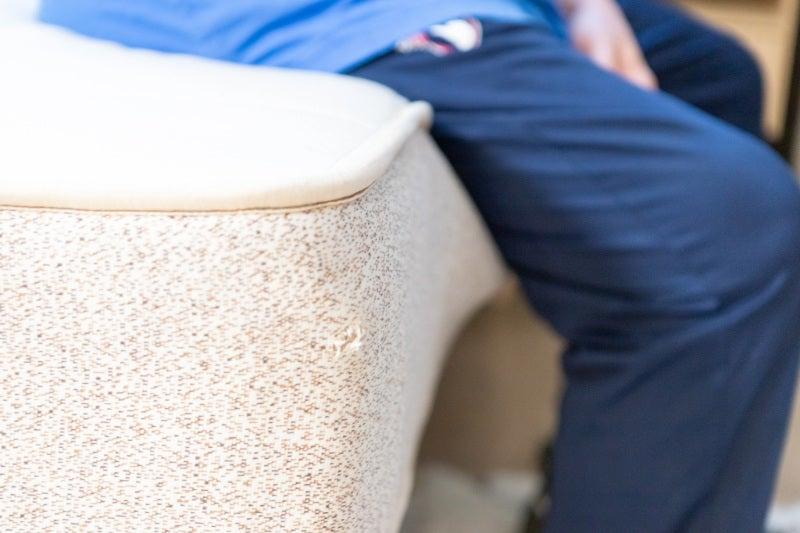 A man sitting on the edge of the Birch Natural mattress