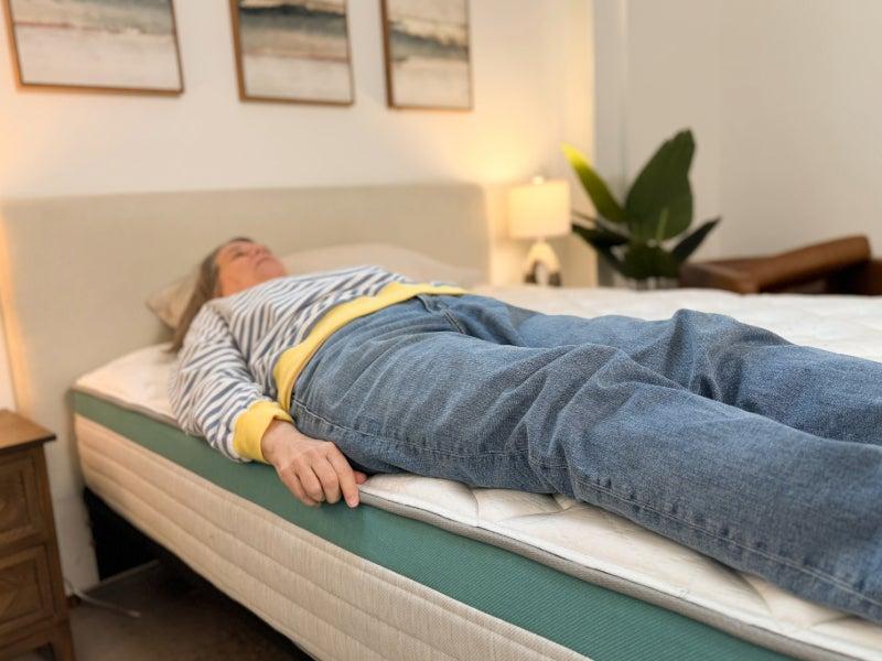 A woman lying on her back on the Helix Sunset mattress