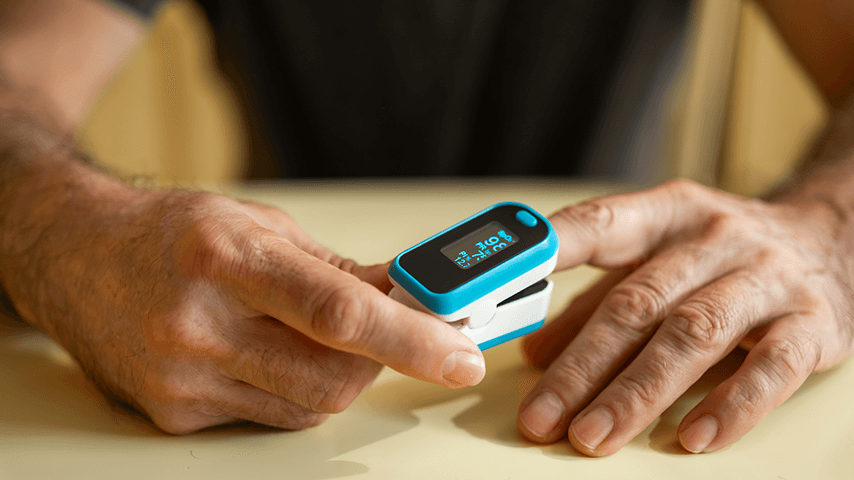 man's hands with pulse oximeter on left index finger