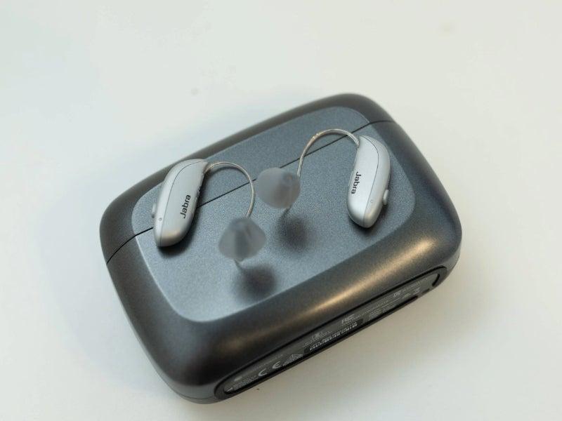 The Jabra Enhance Select M1 hearing aids resting on top of their portable charging case