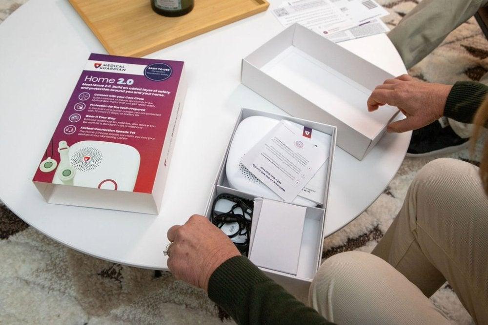 A person taking the Medical Guardian Home 2.0 system out of the box