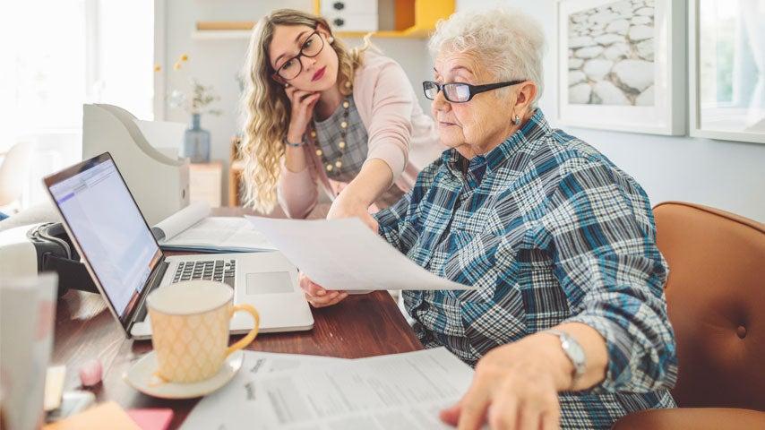 A senior woman is getting online tax refund help from a younger lady.