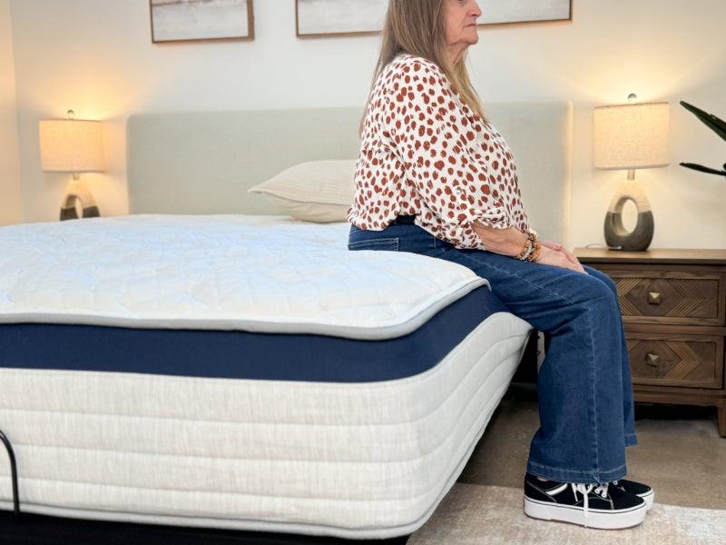A woman sitting on the edge of the Helix Midnight mattress