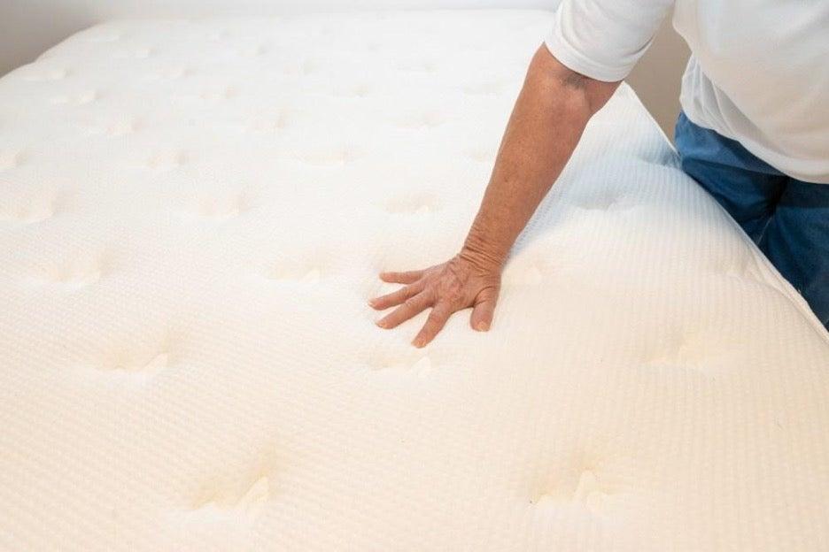 A tester pushing down on the Brooklyn Bedding Signature Hybrid mattress