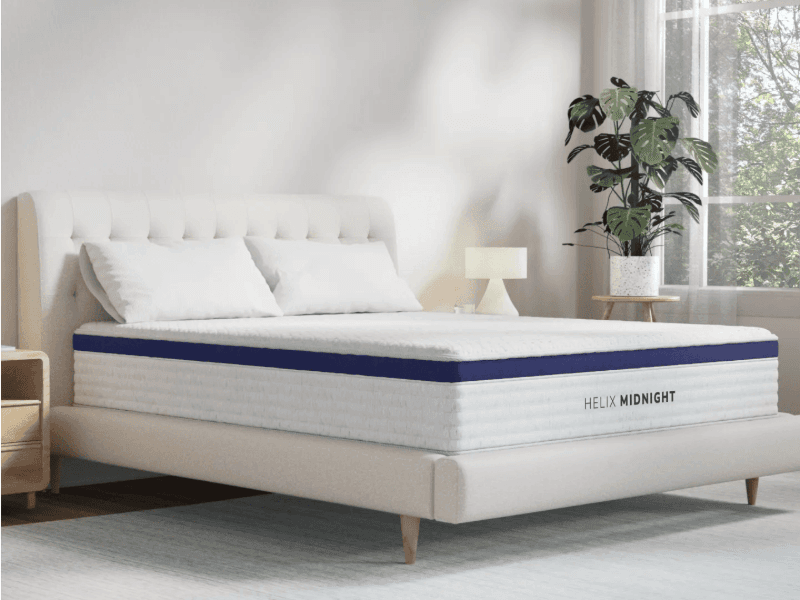 The Helix Midnight mattress in a white room with a plant in the background