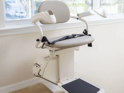 A Harmar stair lift at the top of a set of indoor stairs