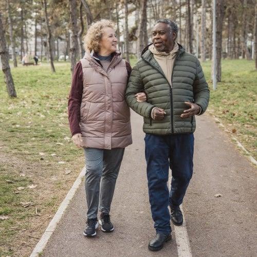 A man and woman walk on a trail together and share a conversation