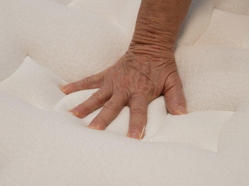 A hand pressing into the pillow top of the Nolah Evolution mattress