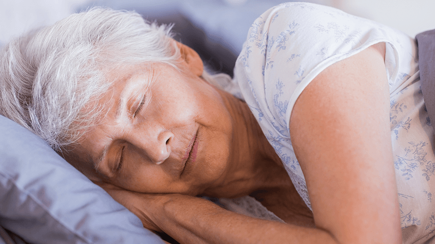 gray haired woman asleep with hands under her head on a pillow
