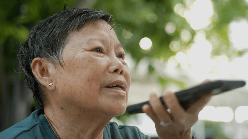 older Asian woman talking to AI assistant on cellphone