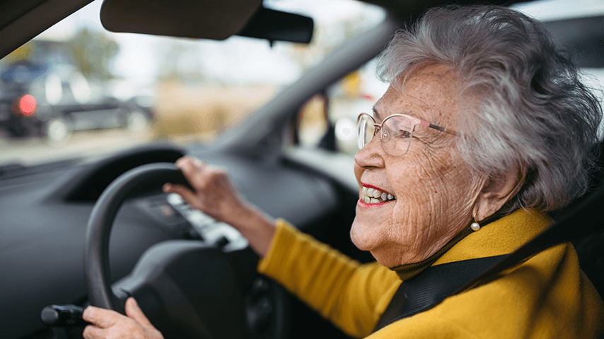smiling older woman behind the wheel of a car