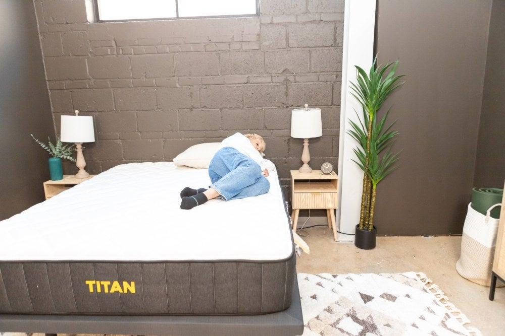 A woman lies on her side on the Titan Plus mattress