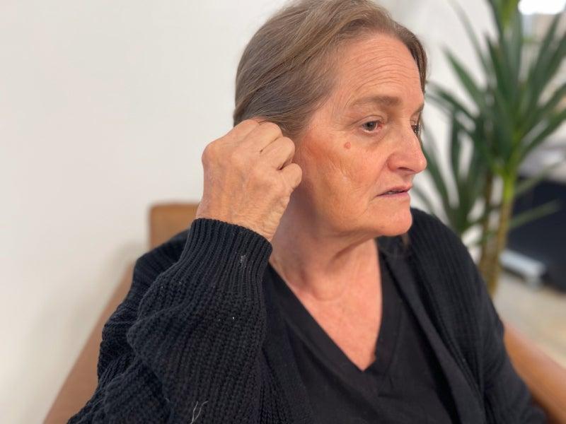 A woman adjusting the Eargo SE hearing aid in her ear