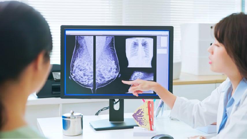 A healthcare provider points to radiology results on a screen.
