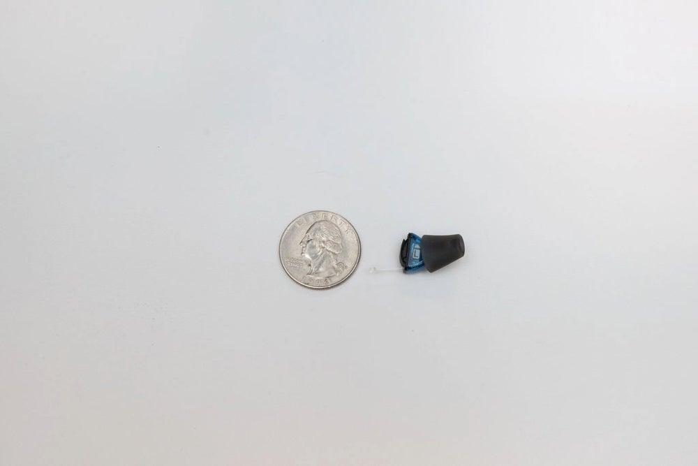 hearing aid next to a quarter coin