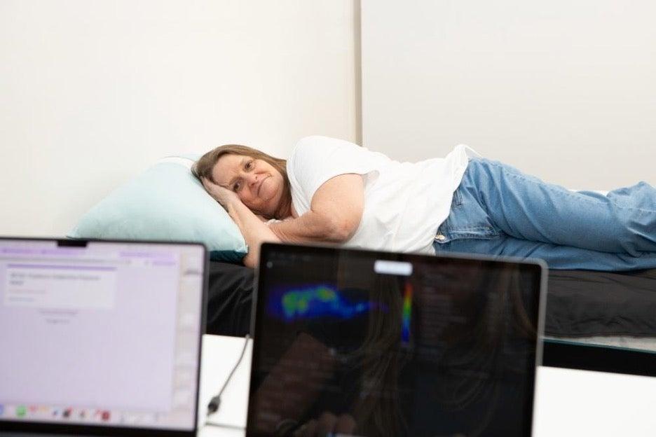A woman lies on a pressure mat on her side to test the Nectar Premier Memory Foam mattress.