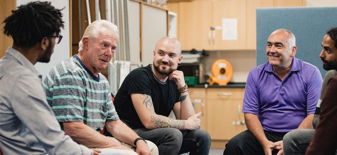 Five men in a circle, engaged in conversation.