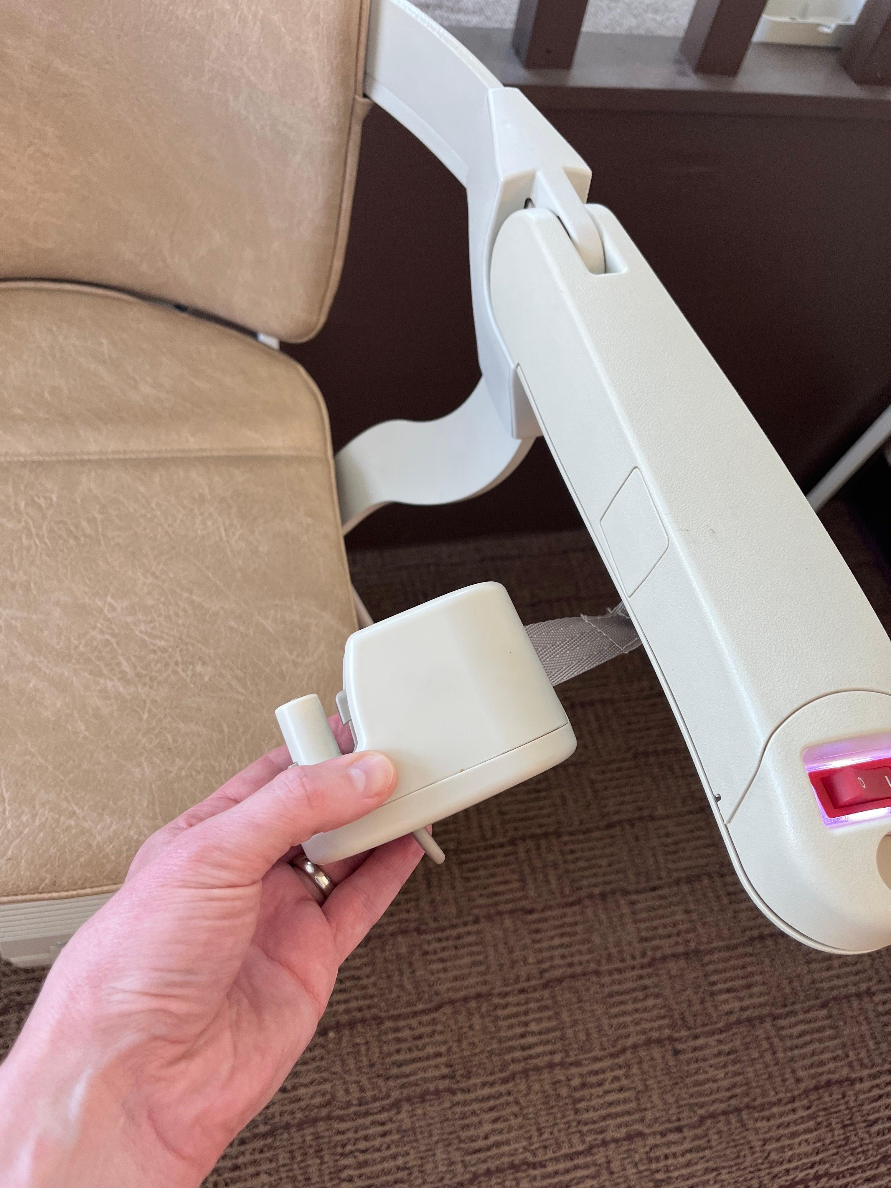 Hand pulling an accessible Stannah stair lift seat belt for inspection