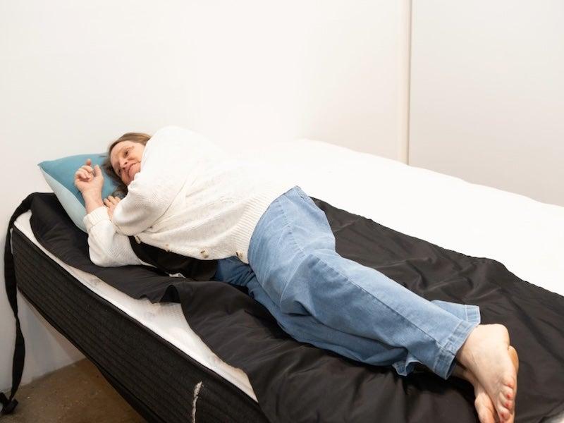 A woman lies on her side on a pressure map on the Plank Firm mattress