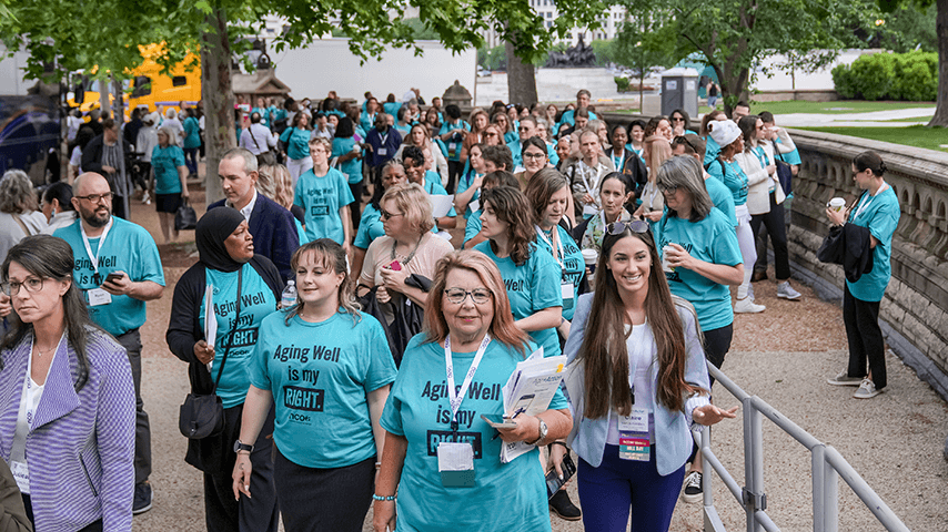group of smiling advocates wearing "Aging Well is my Right" T-shirts walking near Capitol