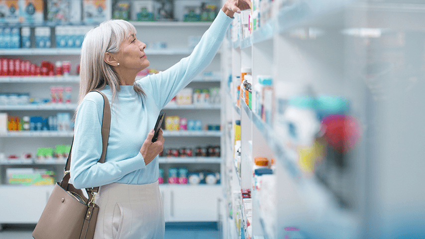 older woman looking at supplements on pharmacy shelves
