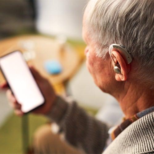A person wearing hearing aids and looking at a smartphone