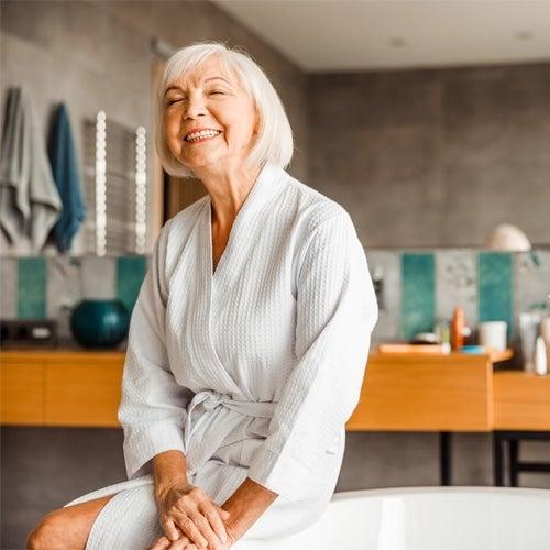 Woman smiles wearing her bathrobe in her modern bathroom