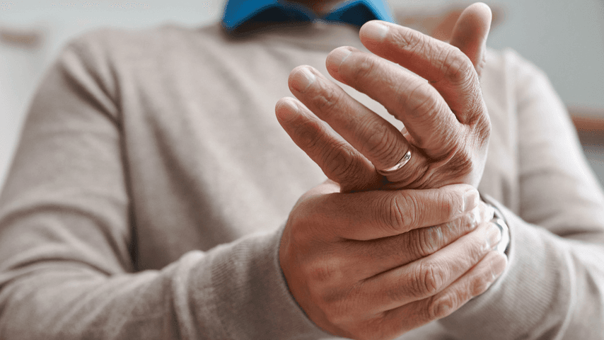 An older man massages his hand