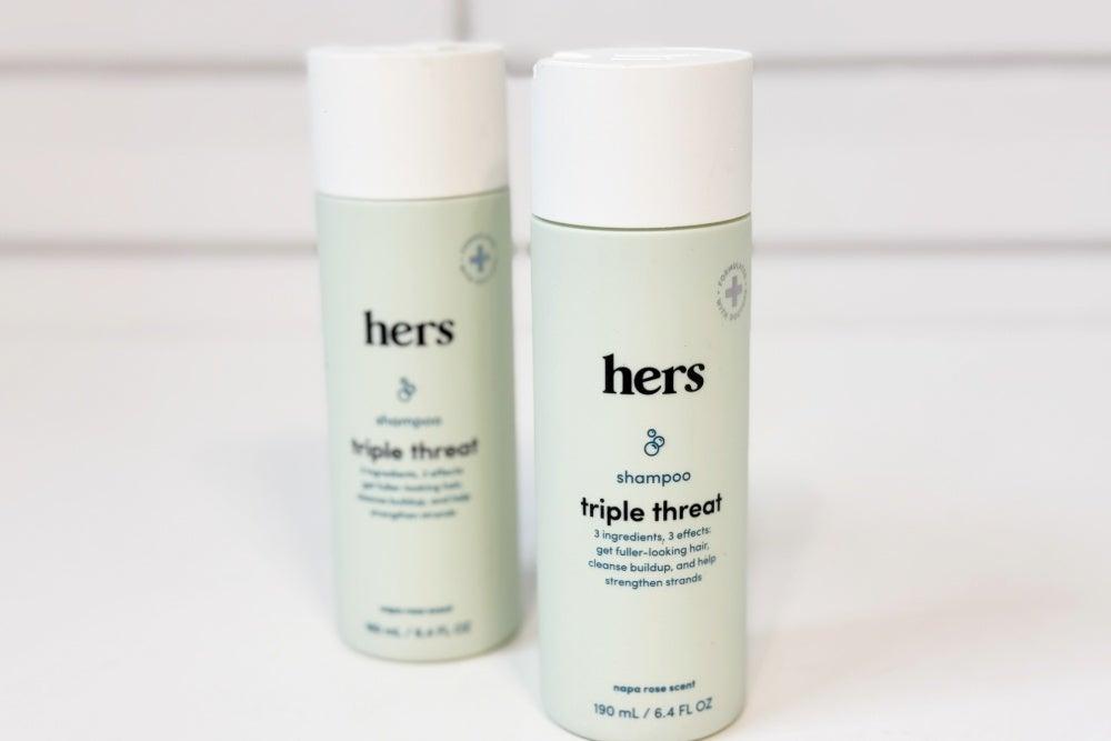 Hers Triple Threat Shampoo and Conditioner bottles on a white countertop