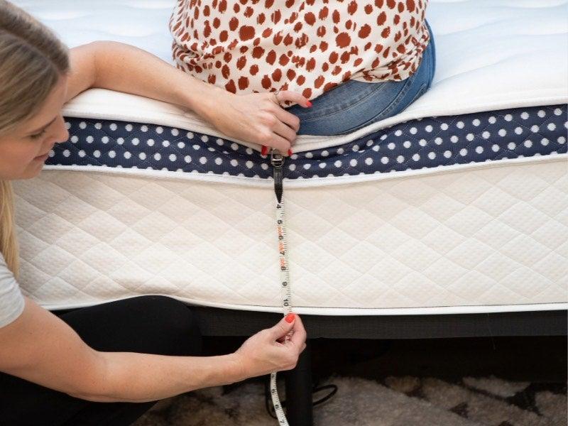 A woman measures how far the edge of the WinkBed Plus sinks when someone is seated on the edge