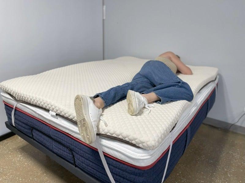 A woman lies on her side on the Nolah topper