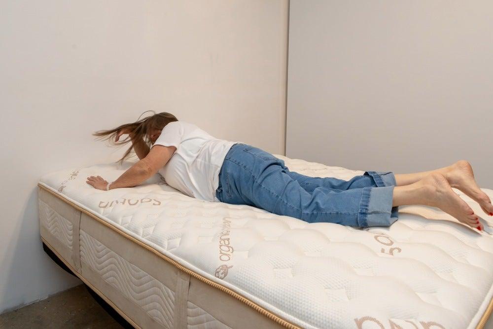 An older adult woman rolling over on the Saatva Rx mattress