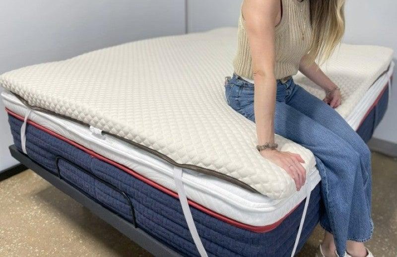 A woman tests the edge support of the Nolah mattress topper