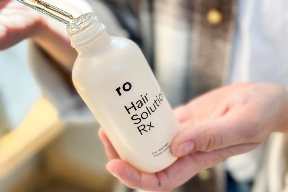 A person holding a bottle of Ro Hair Solution Rx