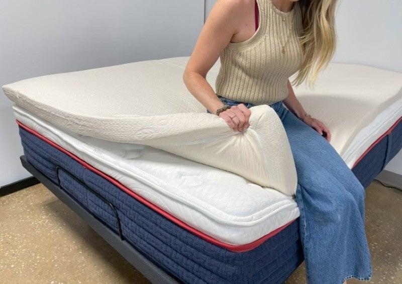 A woman bends the corner of the Avocado mattress topper