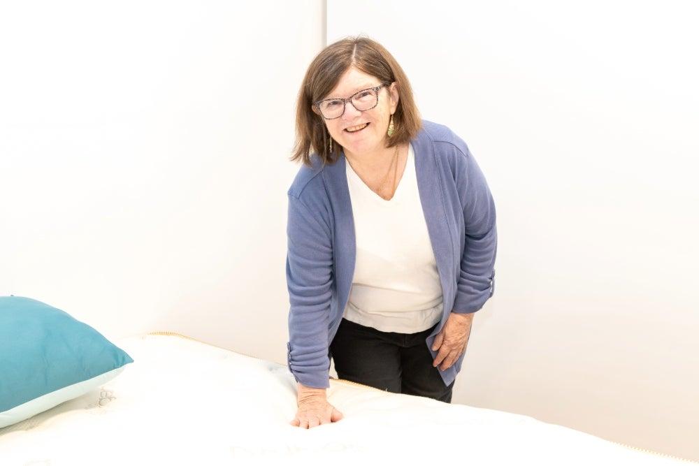 woman pressing down on the top of the Saatva Classic mattress