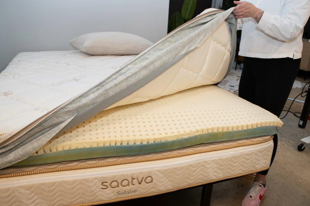 A person holding up the cover of the Saatva Solaire mattress to show its layers
