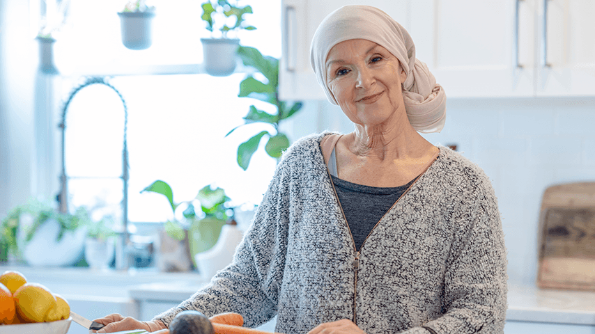 Smiling older woman in head wrap standing in kitchen