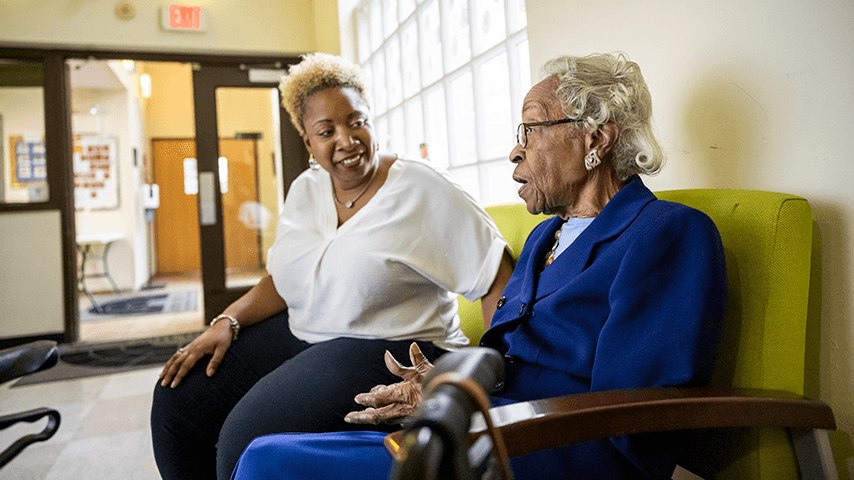 two women seated on bench and talking