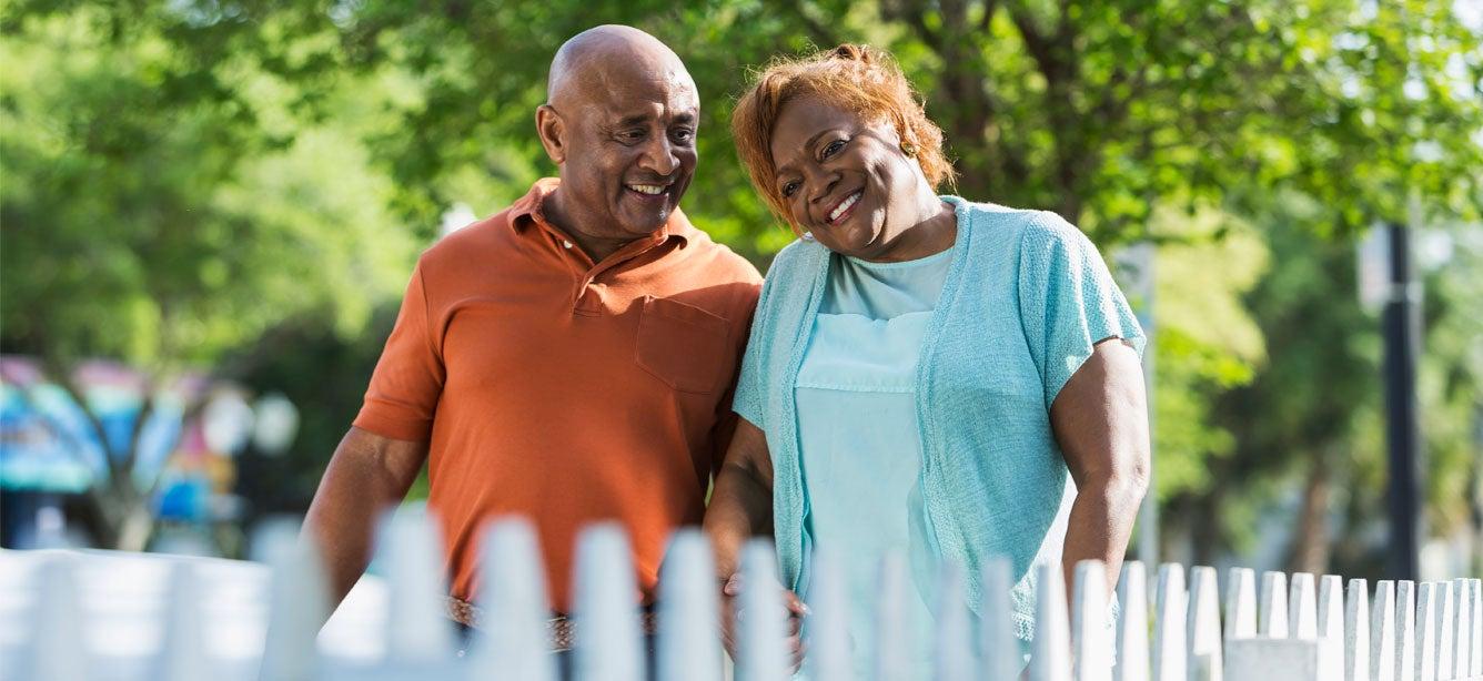 Senior African American couple holding hands walking outside.